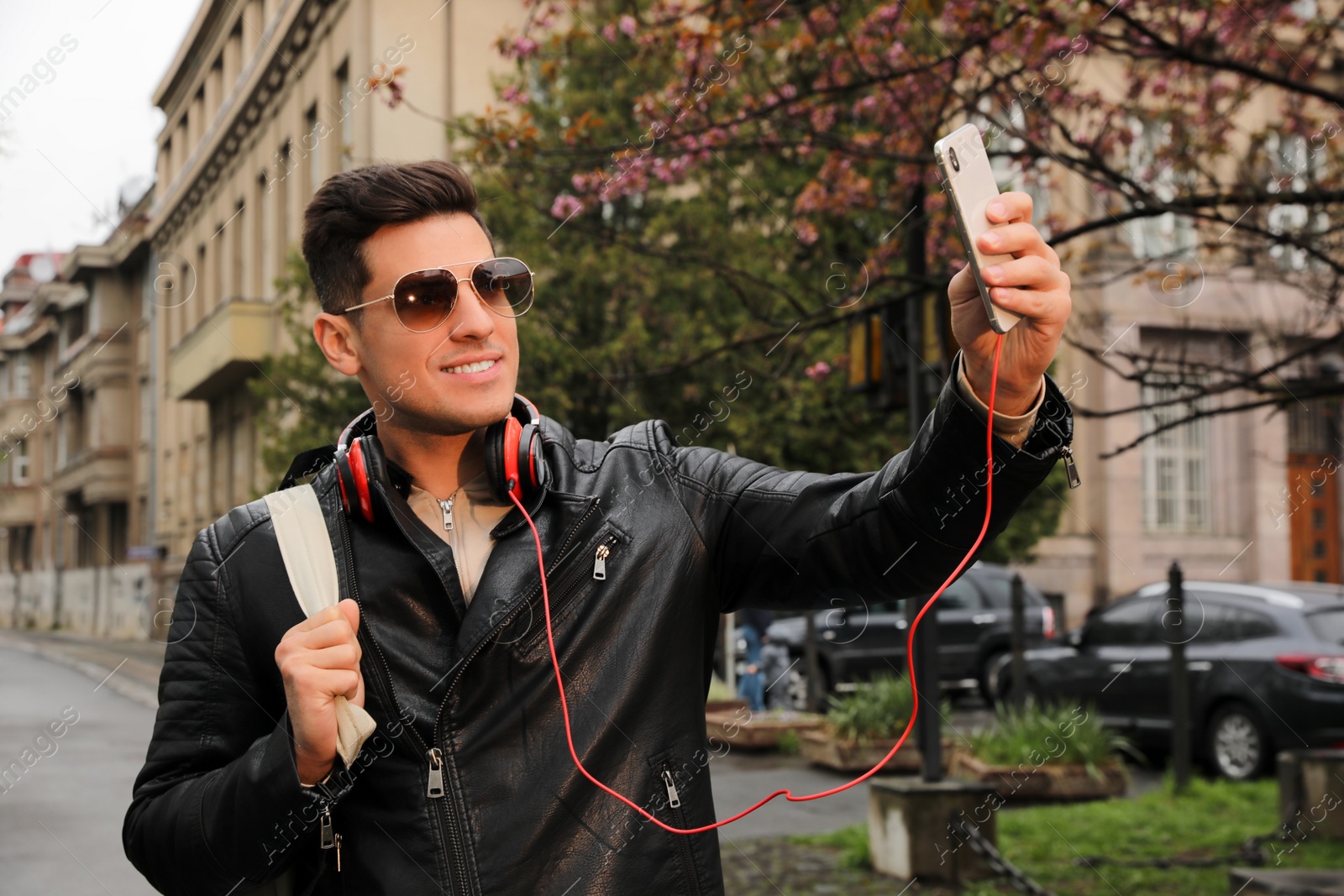 Photo of Tourist with smartphone taking selfie on city street