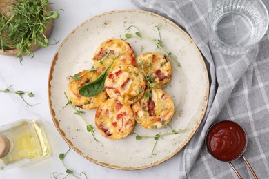 Freshly baked bacon and egg muffins with cheese served on white marble table, flat lay