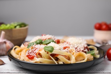 Photo of Delicious pasta with tomato sauce, basil and parmesan cheese on white wooden table