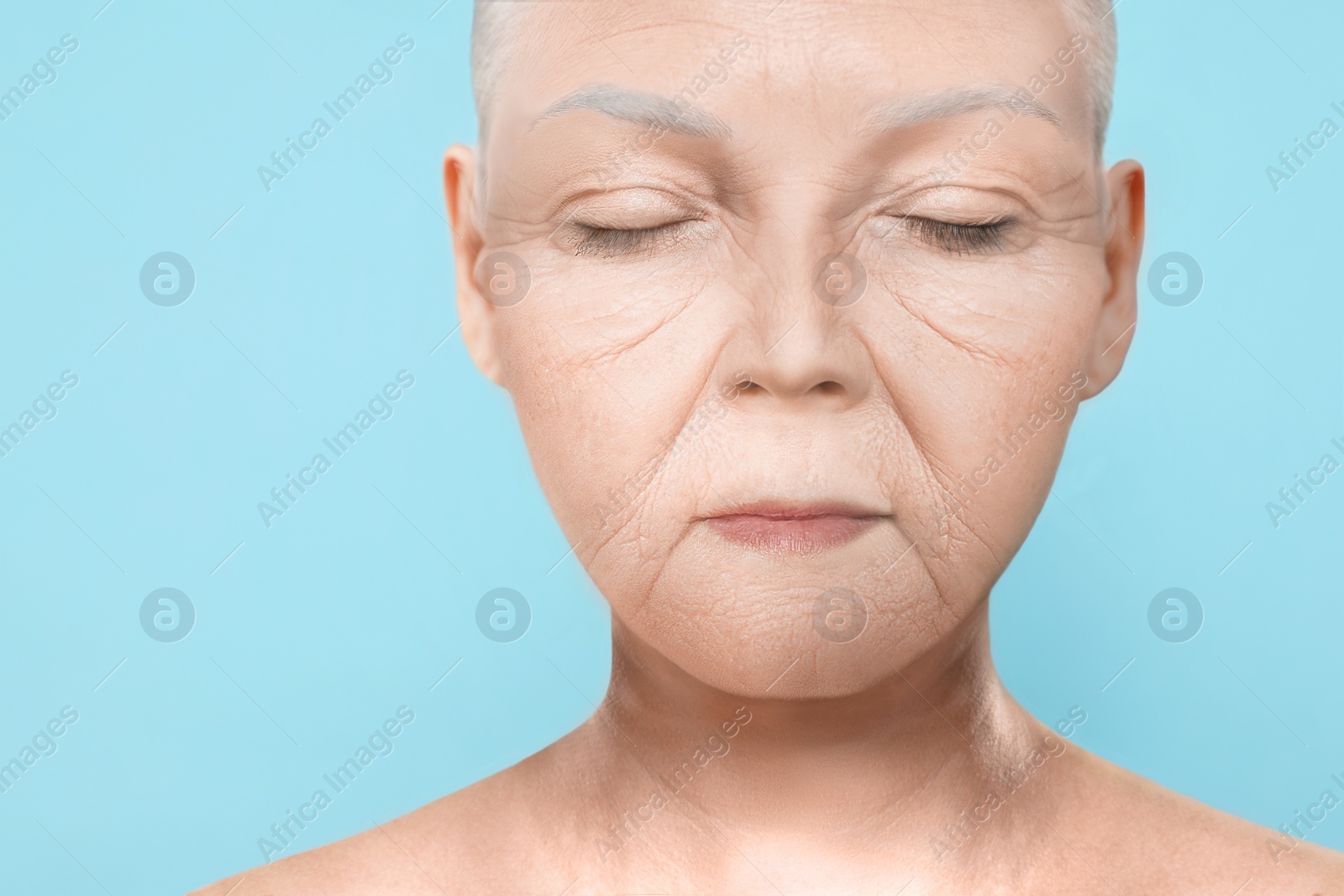 Image of Portrait of senior woman on light blue background