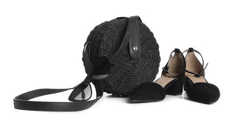 Stylish black handbag with shoes and sunglasses isolated on white