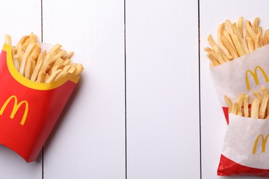 Photo of MYKOLAIV, UKRAINE - AUGUST 12, 2021: Small and big portions of McDonald's French fries on white wooden table, flat lay. Space for text