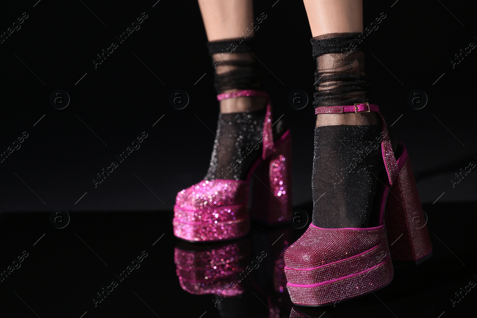 Photo of Woman wearing pink high heeled shoes with platform and square toes on black background, closeup. Space for text