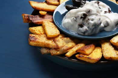 Photo of Delicious parsnips and prunes in cream sauce on blue wooden table, closeup