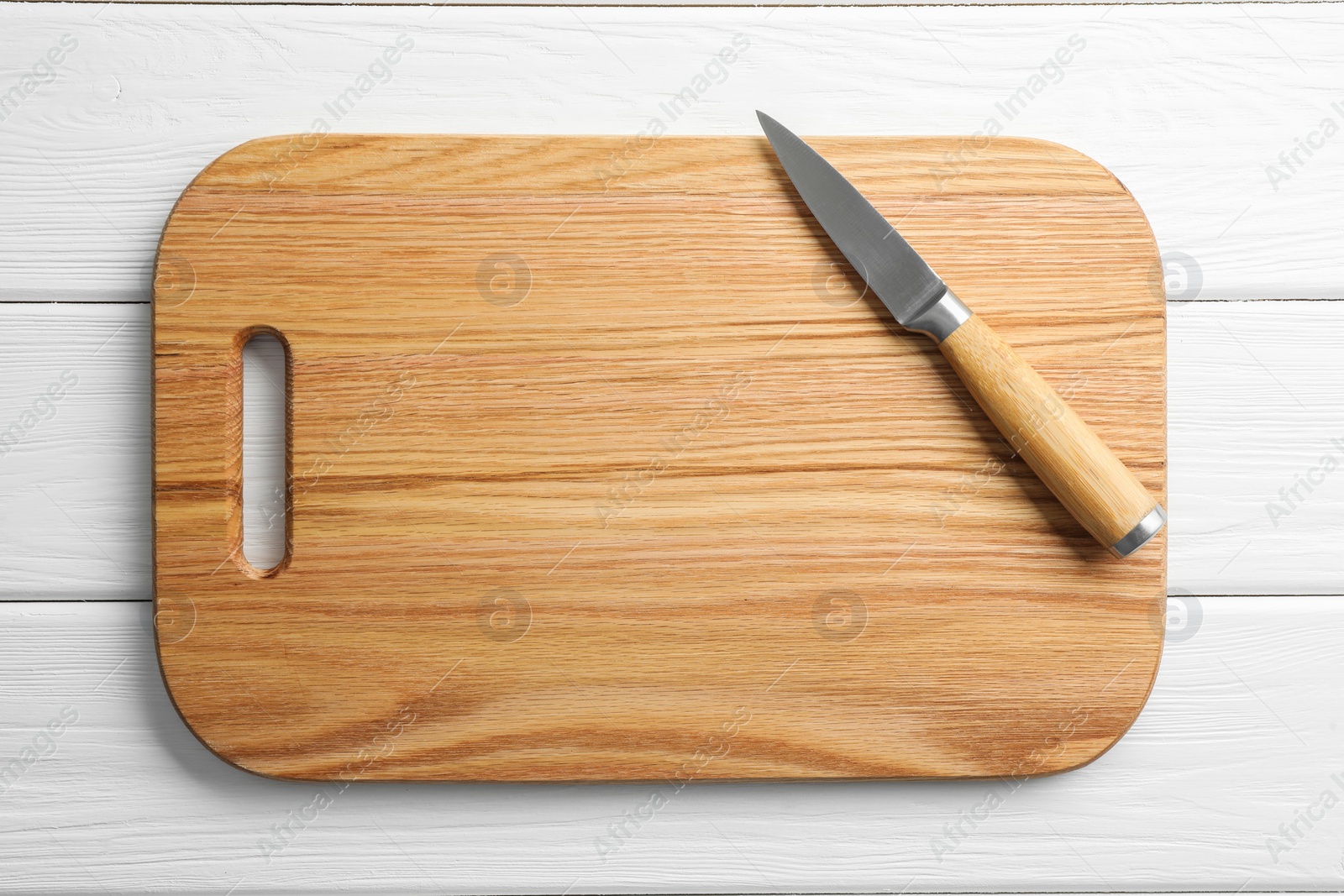 Photo of One sharp knife and board on white wooden table, top view