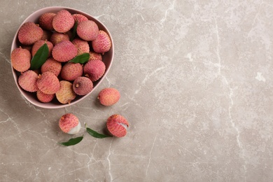 Photo of Fresh ripe lychee fruits on grey table, flat lay. Space for text