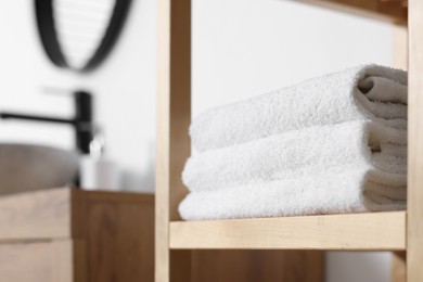 Photo of Stacked bath towel on wooden shelf indoors, closeup. Space for text