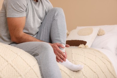 Man suffering from foot pain on bed indoors, closeup