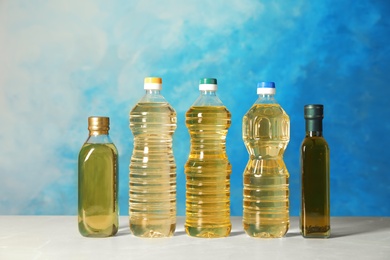 Photo of Bottles of oils on table against color background