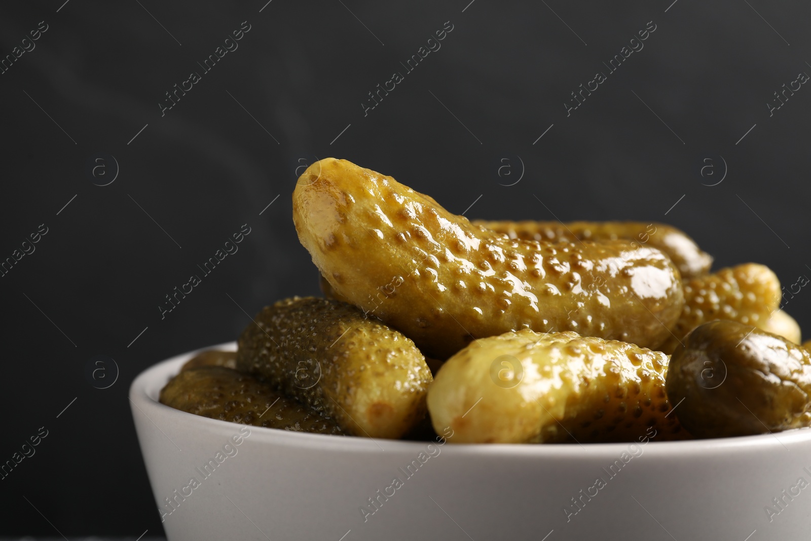 Photo of Tasty pickled cucumbers in bowl on grey background, closeup