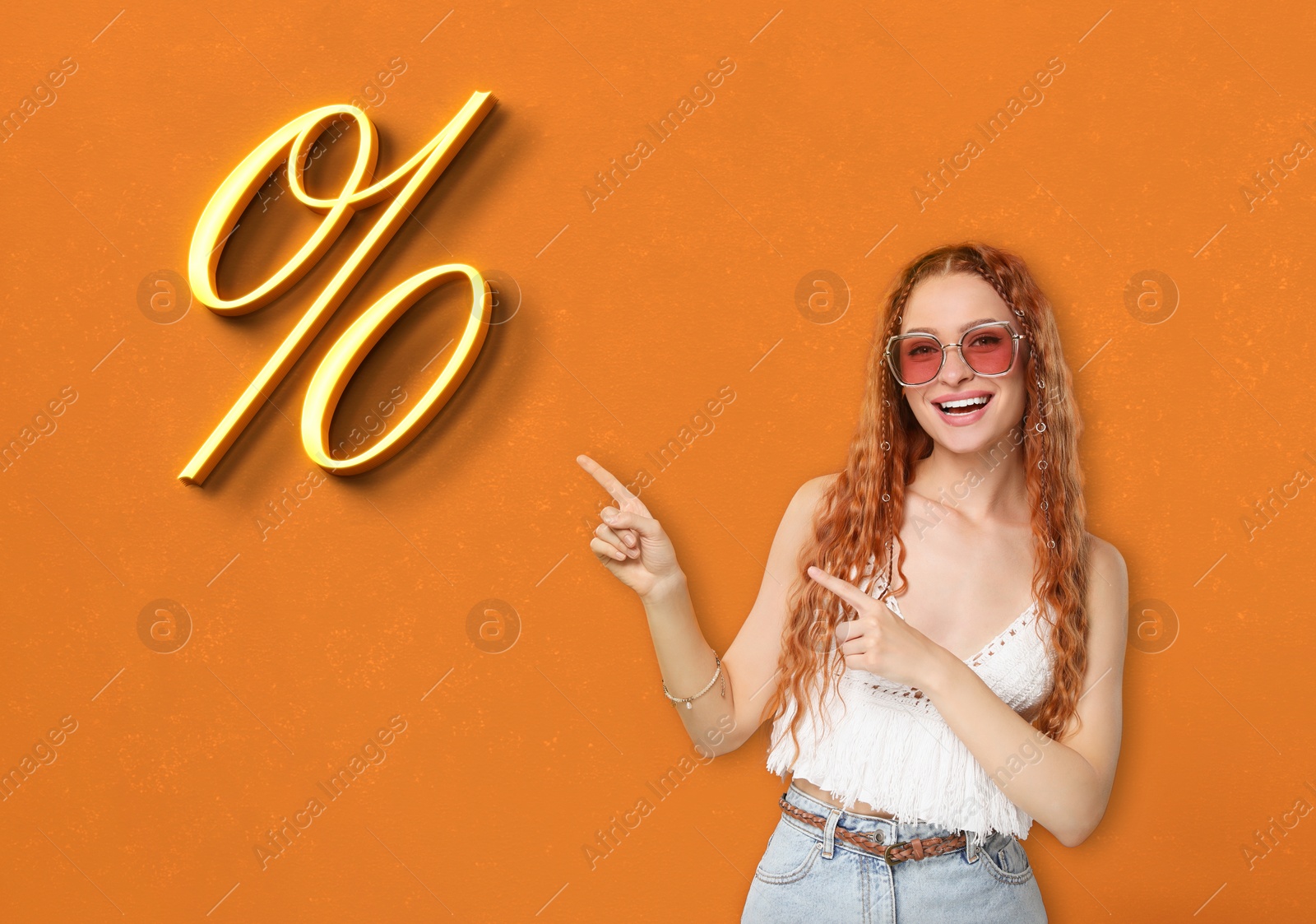 Image of Discount offer. Happy woman pointing at percent sign on orange background