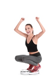 Photo of Happy young woman measuring her weight using scales on white background. Weight loss motivation