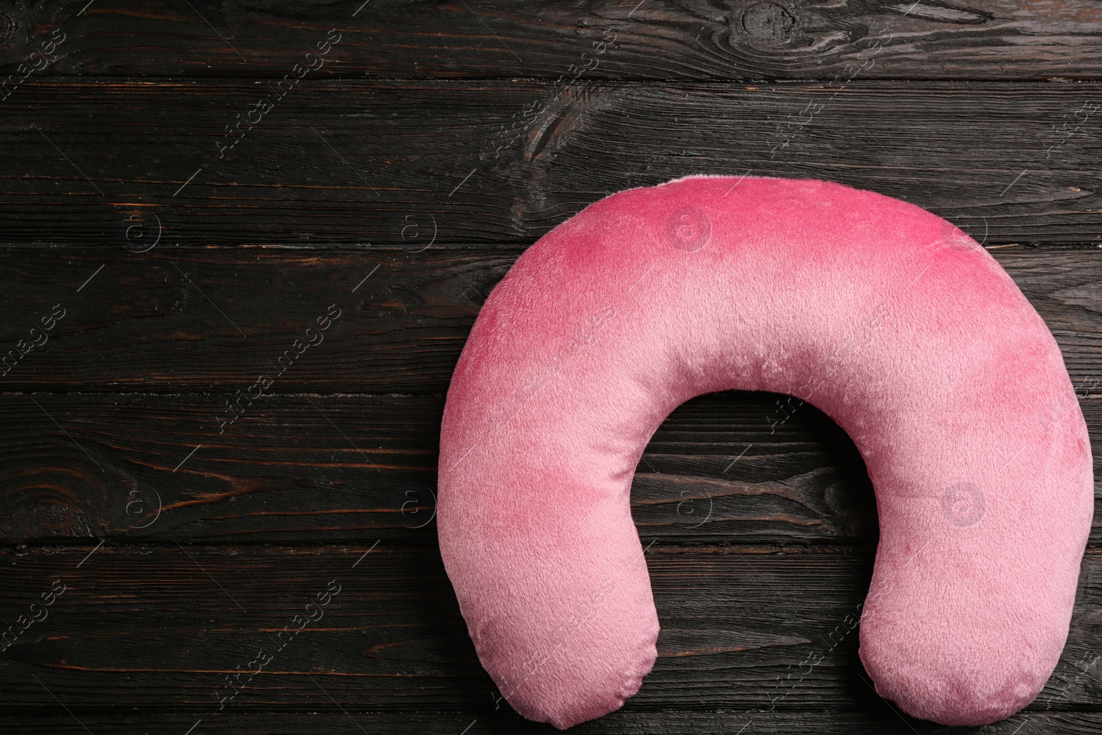 Image of Pink travel pillow on wooden background, top view. Space for text
