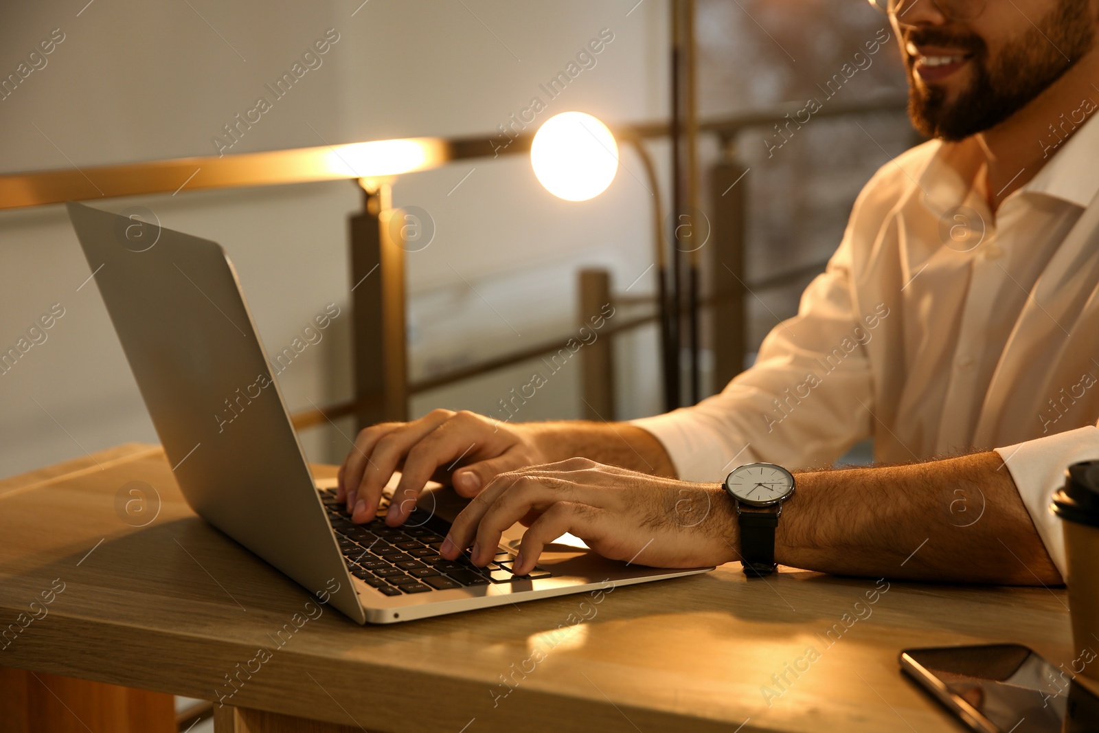 Photo of Man working with laptop at table in office, closeup