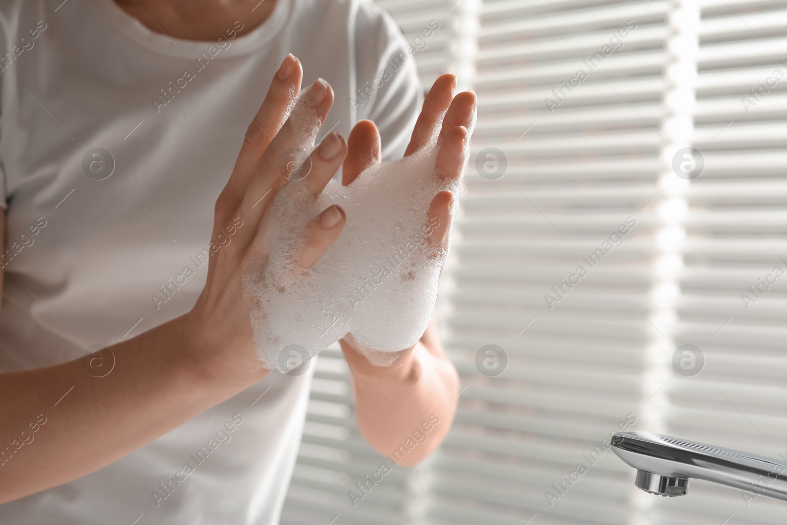 Photo of Woman washing hands with cleansing foam near sink in bathroom, closeup