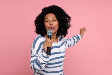 Photo of Beautiful woman with microphone singing on pink background