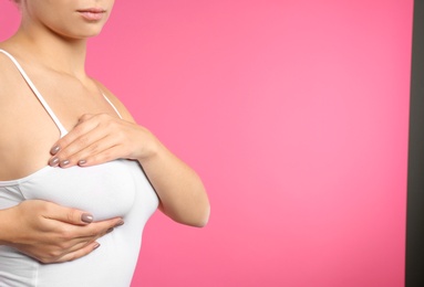 Photo of Woman checking her breast on color background, closeup. Space for text