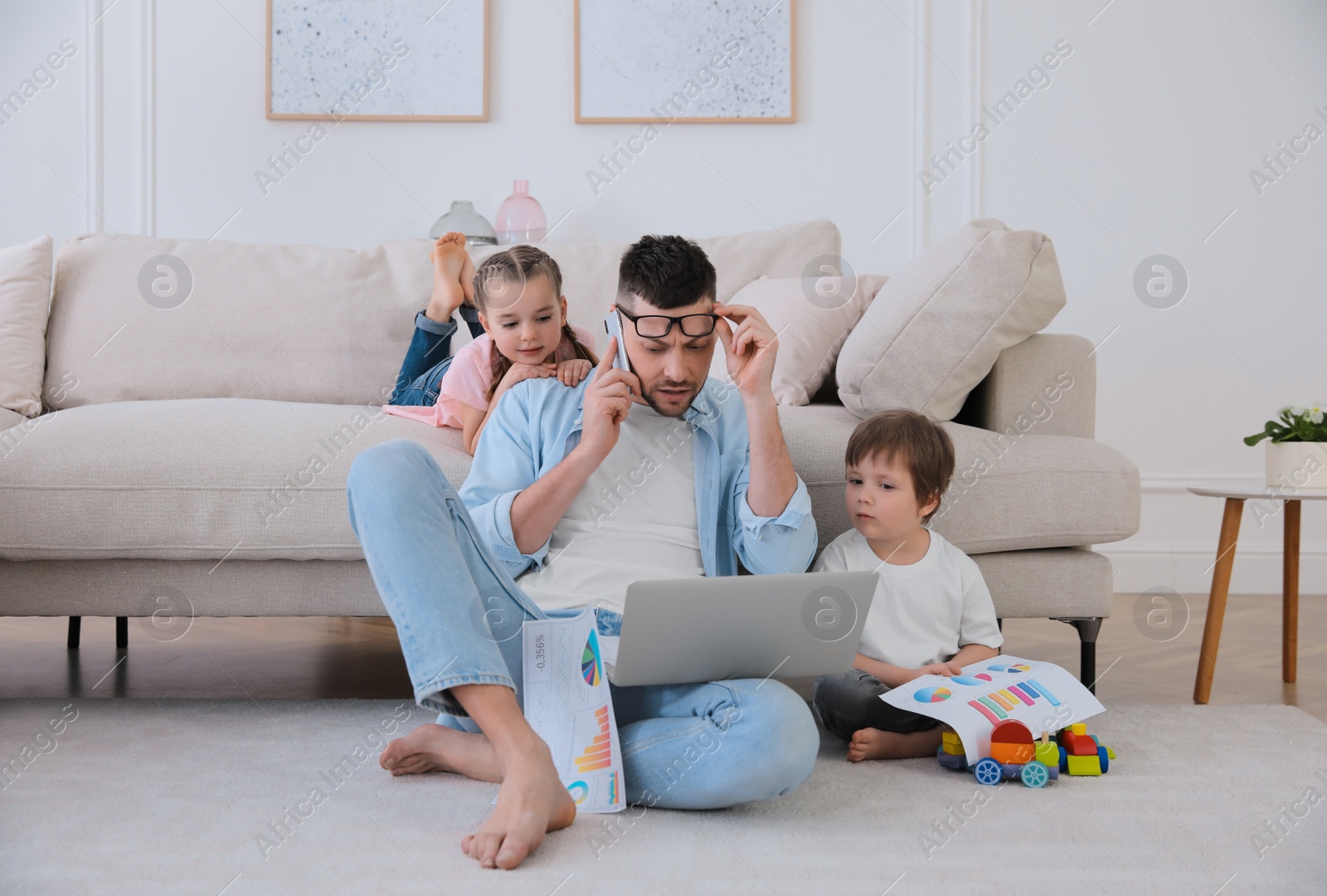 Photo of Overwhelmed man combining parenting and work at home