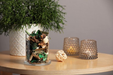 Glass jar with aromatic potpourri of dried flowers and beautiful houseplant on wooden table indoors