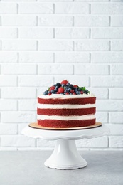 Stand with delicious homemade red velvet cake near brick wall