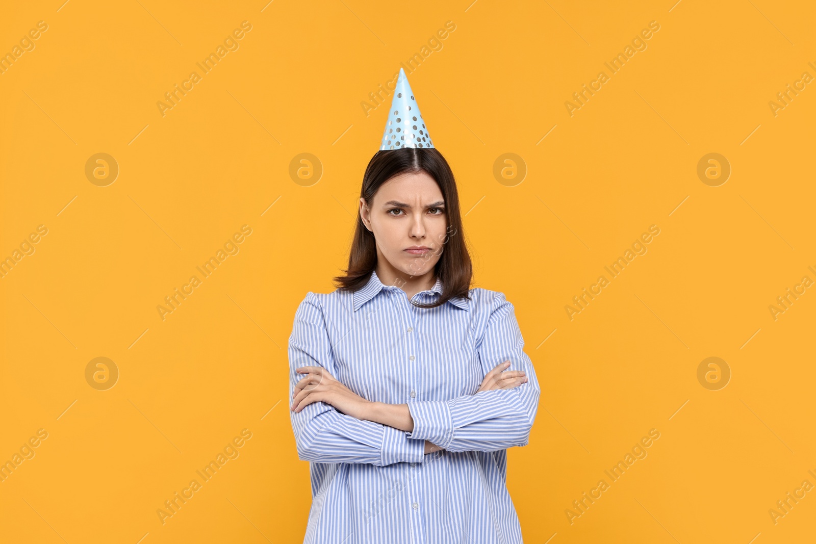 Photo of Sad young woman in party hat on yellow background