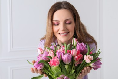 Photo of Young woman with bouquet of beautiful tulips indoors
