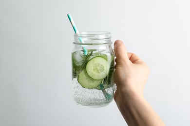 Young woman holding jar with fresh cucumber water on white background. Space for text