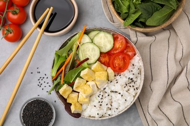 Photo of Delicious poke bowl with vegetables, tofu and mesclun served on light grey table, flat lay