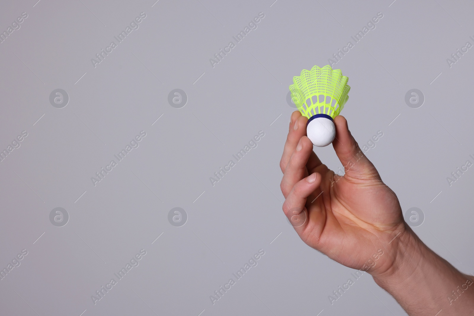 Photo of Man with badminton shuttlecock on light grey background, closeup. Space for text