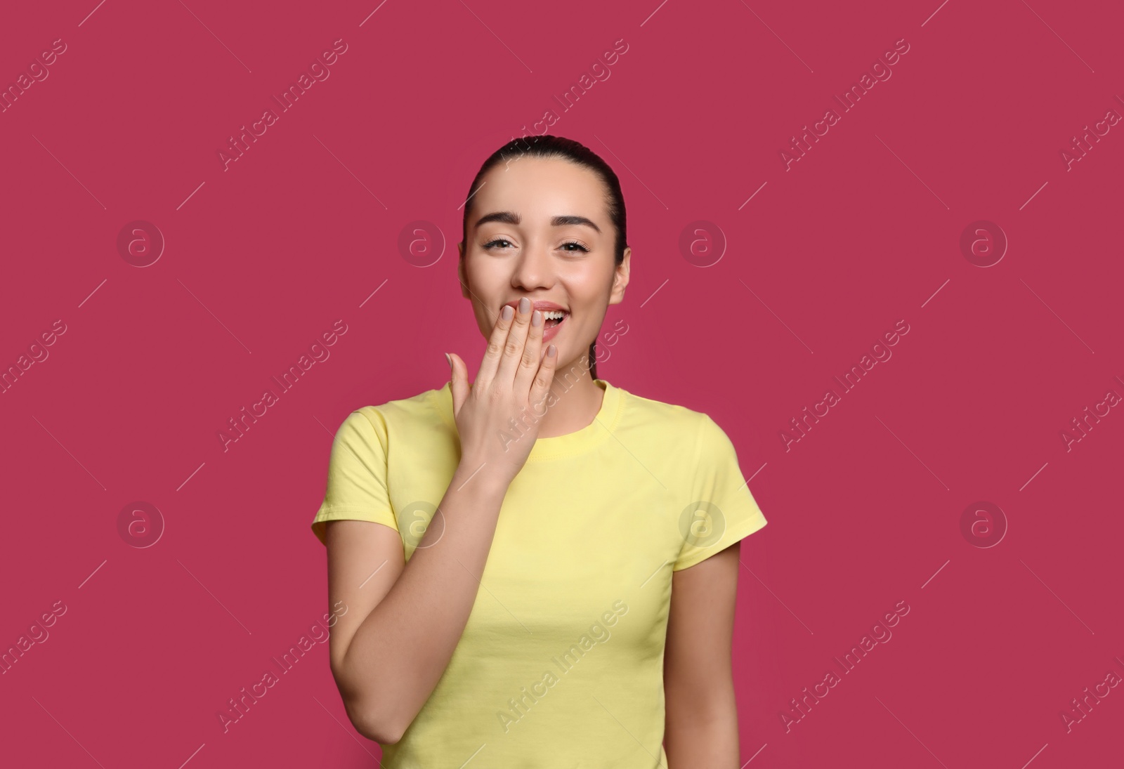 Photo of Beautiful young woman laughing on maroon background. Funny joke