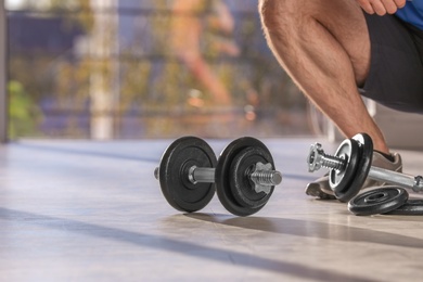 Photo of Male athlete with adjustable dumbbells indoors. Space for text