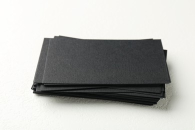 Photo of Blank black business cards on white table, closeup