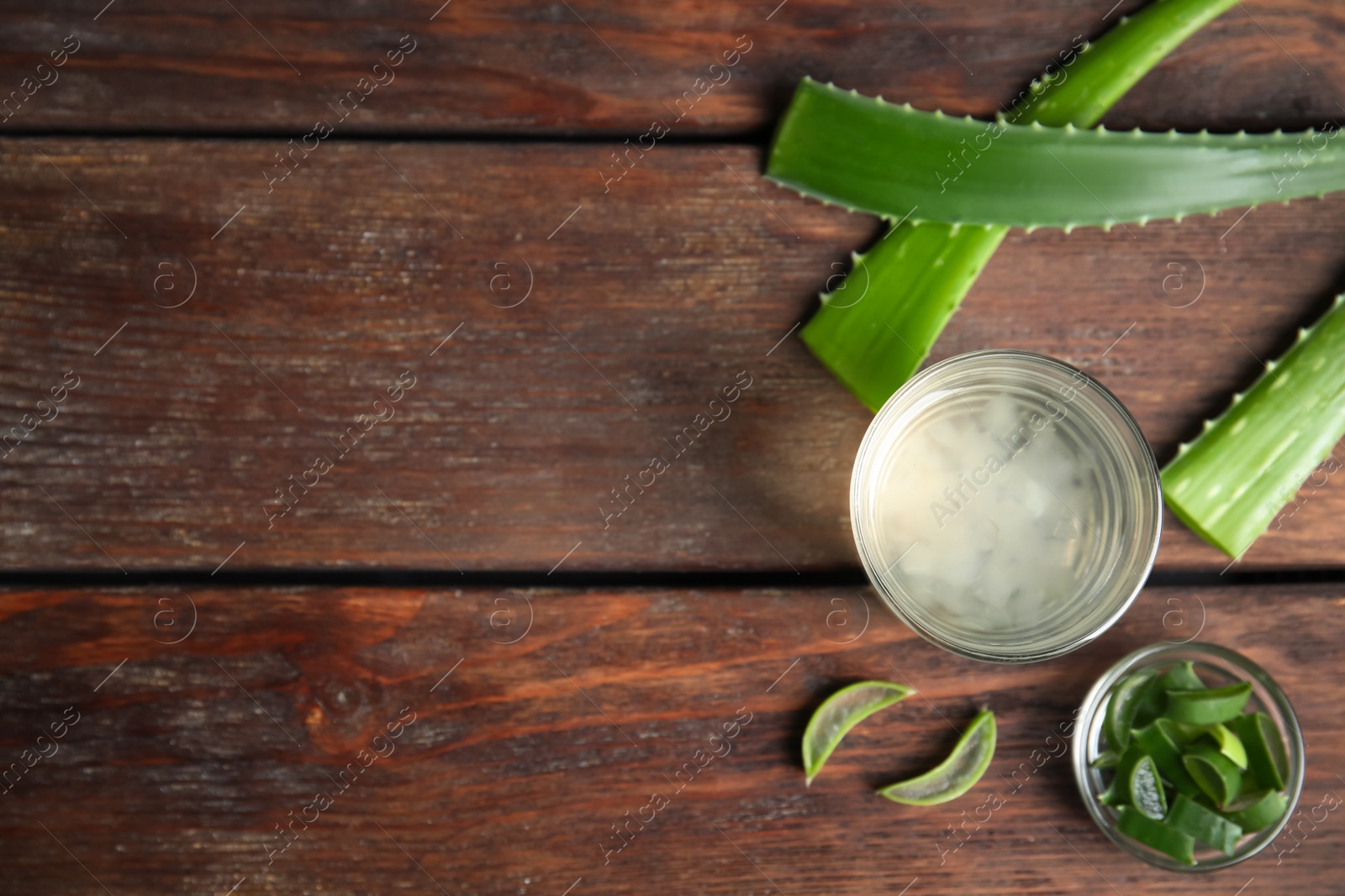 Photo of Fresh aloe drink in glass and leaves on wooden table, flat lay. Space for text