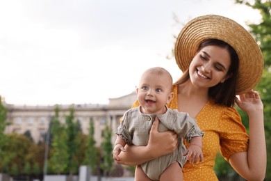 Photo of Happy mother with adorable baby walking on sunny day, space for text