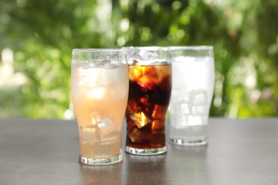 Delicious refreshing drinks in glasses on grey table outdoors