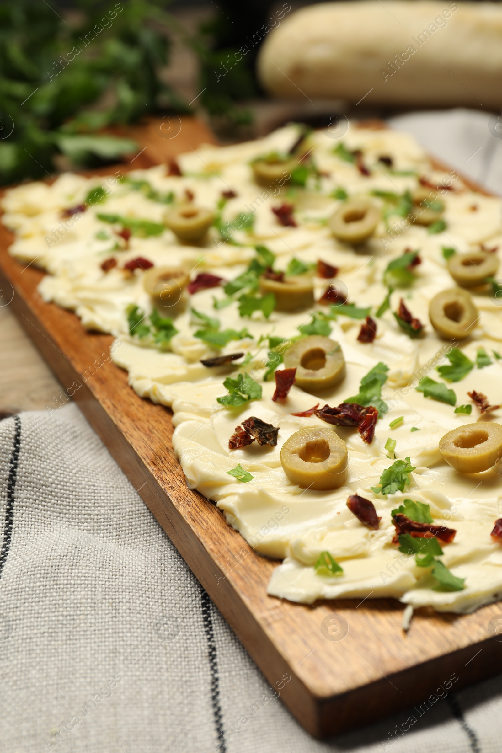 Photo of Fresh butter board with cut olives, sun-dried tomatoes and parsley on table, closeup