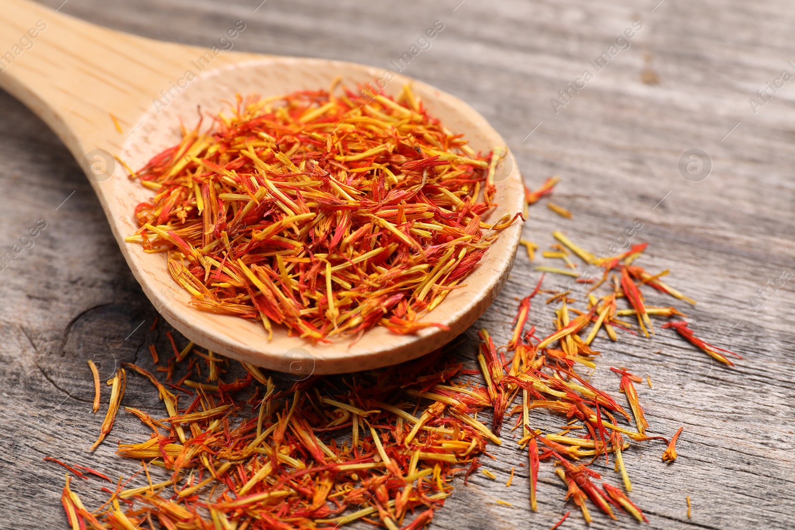 Photo of Aromatic saffron and spoon on wooden table, closeup