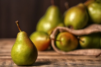 Photo of Fresh ripe pear on wooden table against blurred background