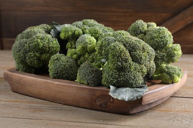 Photo of Tray with fresh raw broccoli on wooden table, closeup