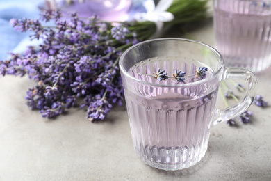 Photo of Fresh delicious drink with lavender in glass cup on grey table