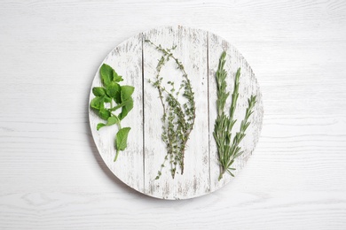 Photo of Board with rosemary, mint and thyme on wooden background, flat lay. Aromatic herbs