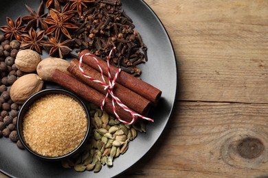 Dishware with different spices on wooden table, top view. Space for text