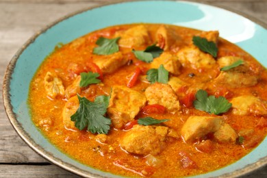 Photo of Delicious chicken curry on wooden table, closeup