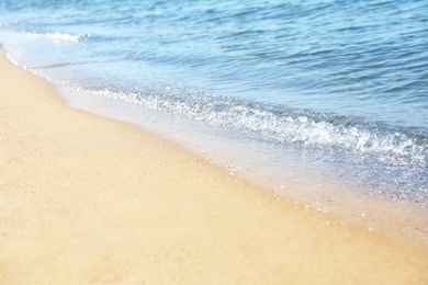 View of sea water and beach sand on sunny day