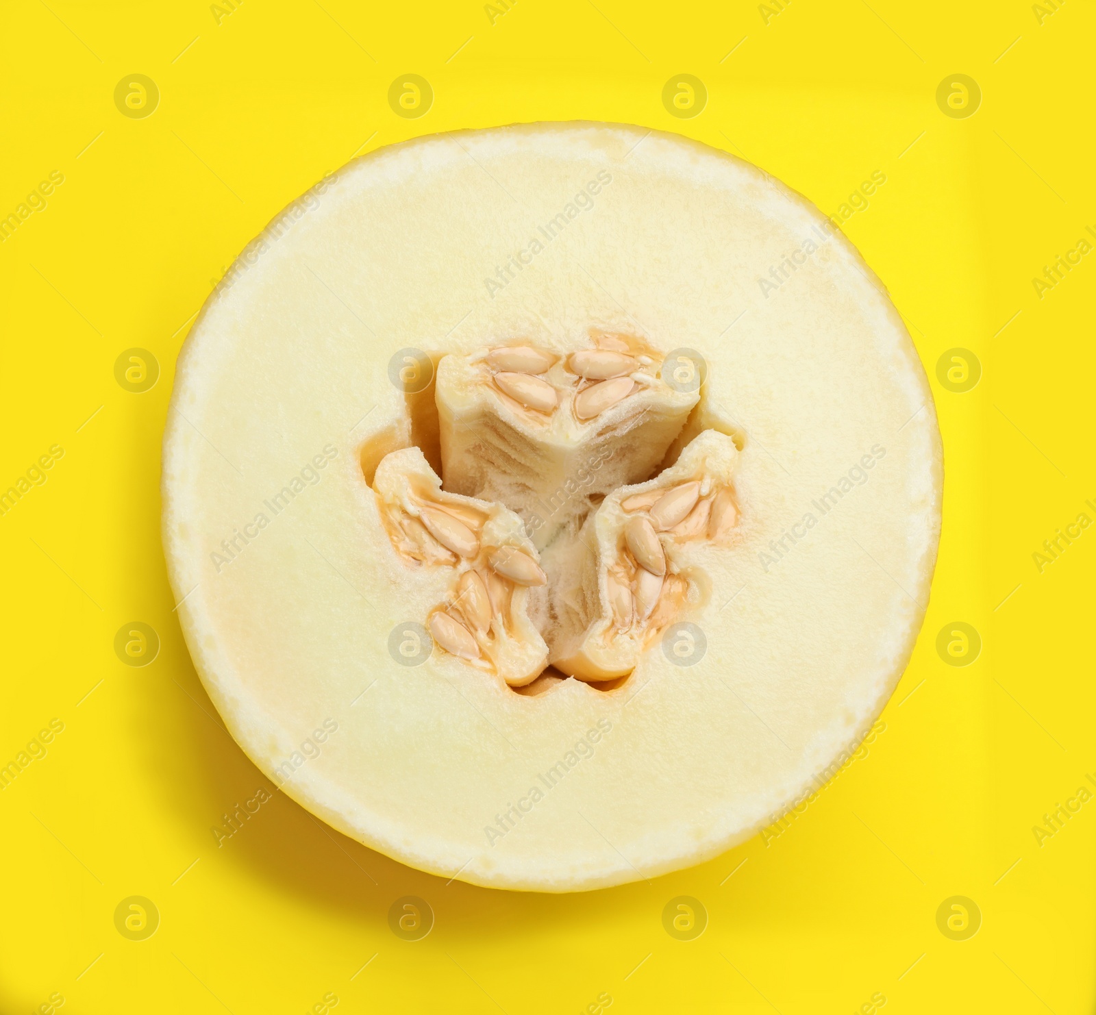 Photo of Half of ripe tasty melon on yellow background, top view