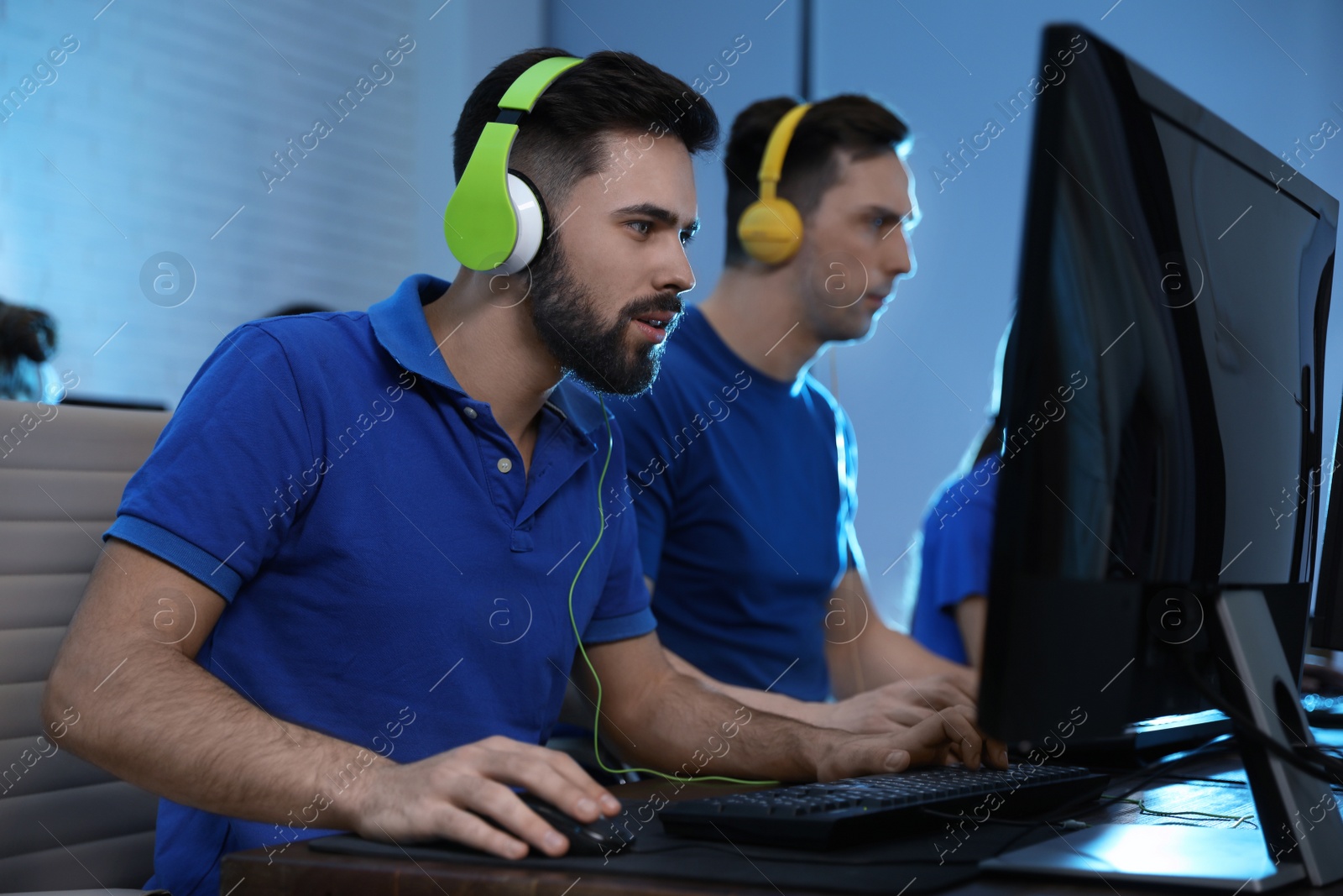 Photo of Young people playing video games on computers indoors. Esports tournament