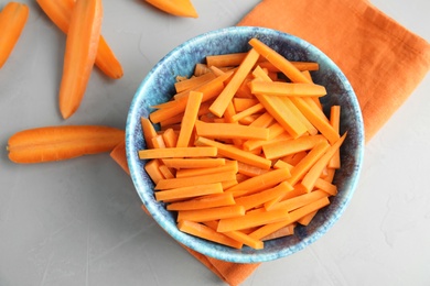 Photo of Bowl with cut ripe carrot on table, top view