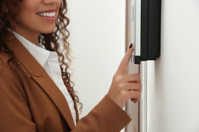 Photo of African-American woman pushing intercom button in entryway, closeup