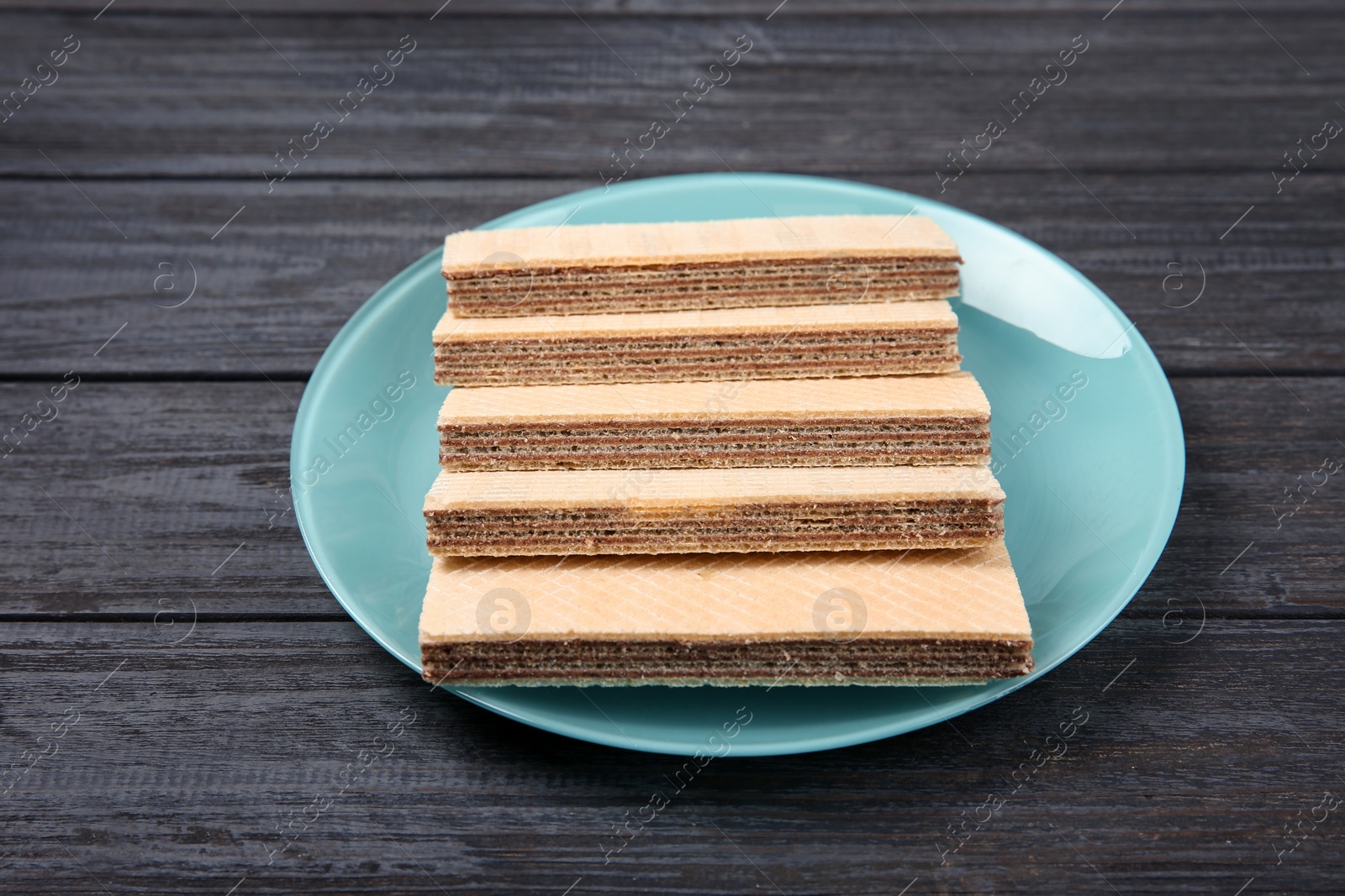 Photo of Plate with delicious crispy wafers on wooden table