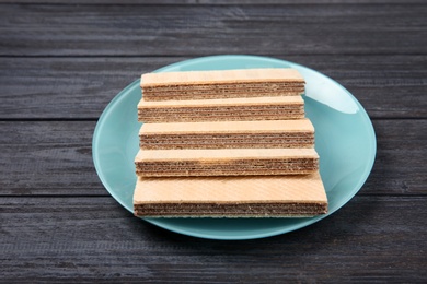 Plate with delicious crispy wafers on wooden table